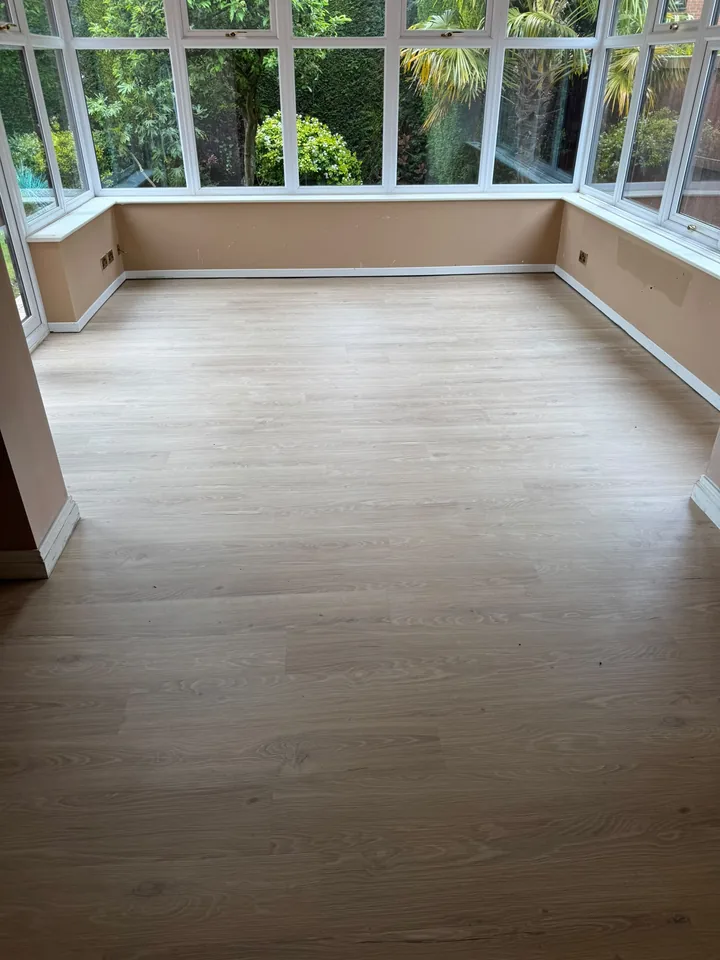 Light wood-effect LVT fitted across a conservatory floor beside garden-facing windows